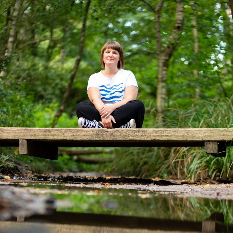 Weitere Methoden der Musiktherapie Claudia Neeten sitzt auf Bank im Wald